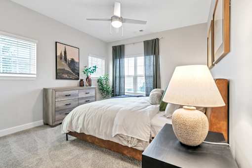 A bedroom with a bed, nightstand, and a painting on the wall.