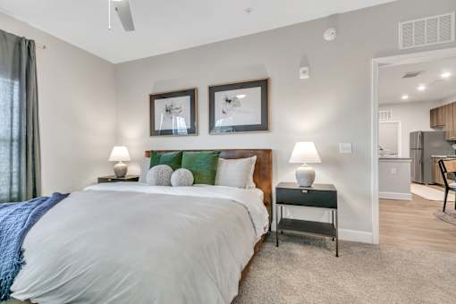 A bedroom with a large bed and two framed pictures on the wall.