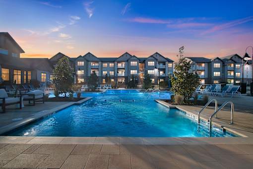 A swimming pool in front of apartment buildings at dusk.