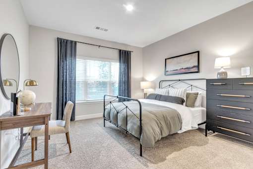 A bedroom with a large bed, a wooden desk, and a chair.