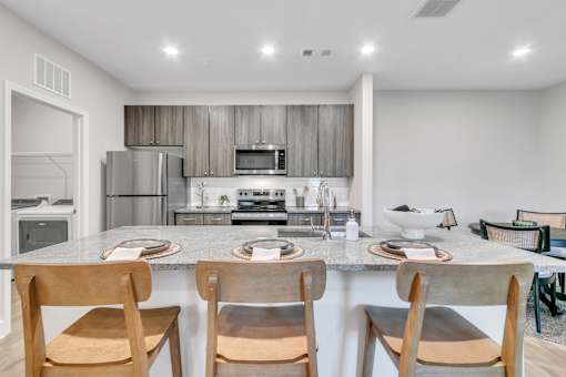 A modern kitchen with wooden chairs and a marble countertop.
