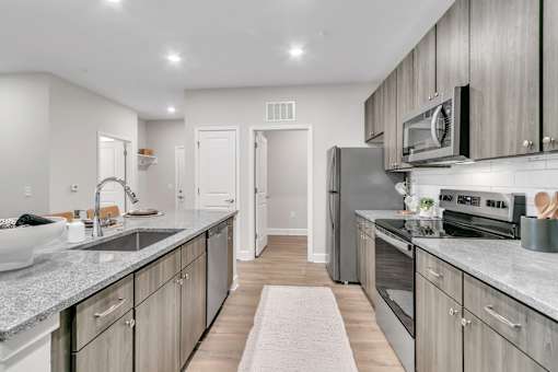 A modern kitchen with a white sink and grey countertops.