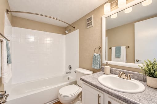 Bathroom with an oval sink and tiled bathtub surround at Waterchase Apartments in Largo, FL.