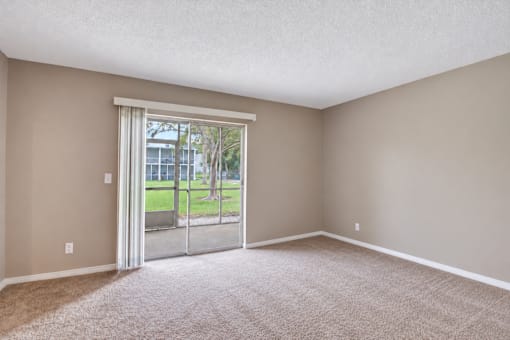 Unfurnished carpeted bedroom with sliding doors to a screened patio at Waterchase Apartments in Largo, FL.