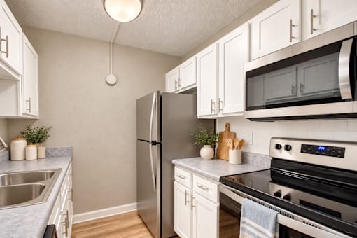 Galley kitchen with white cabinets and a refrigerator at Waterchase Apartments in Largo, FL.