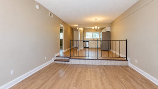 Unfurnished living room with steps and a railing separating the raised dining area at Waterchase Apartments in Largo, FL.