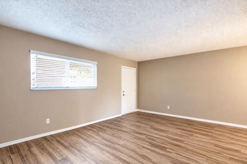 Unfurnished living room with a wide window and wood-look flooring at Waterchase Apartments in Largo, FL.