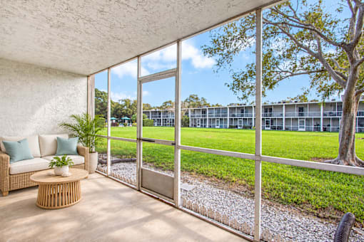 Exterior of Waterchase Apartments in Largo, FL, with trees beneath a blue sky.