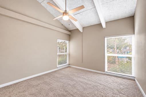 Unfurnished bedroom with exposed ceiling beams, a ceiling fan and carpet at Waterchase Apartments in Largo, FL.