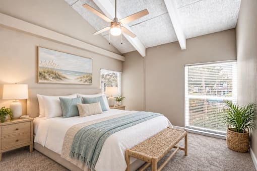 Virtually staged bedroom with a vaulted ceiling, exposed beams, large windows and coastal decor at Waterchase Apartments in Largo, FL.