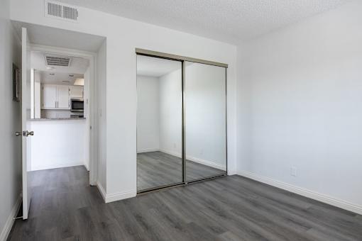 a bedroom with a mirror and a kitchen in the background