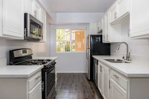 a kitchen with white cabinets and black appliances and a window