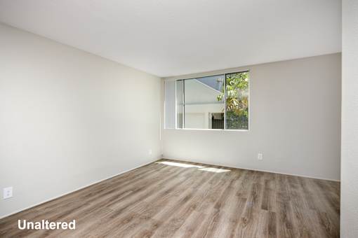 A room with unaltered wooden flooring and a window.