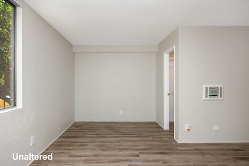 A room with wooden flooring and white walls.