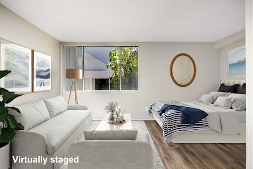 A living room with a grey couch and a white bed.