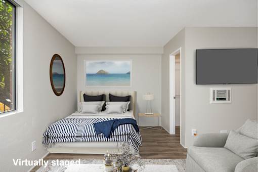 A bedroom with a bed, a couch, and a painting of a beach scene on the wall.