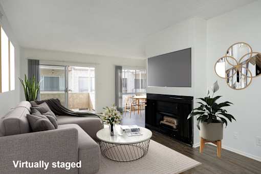 A living room with a grey couch, a black fireplace, and a television mounted on the wall.