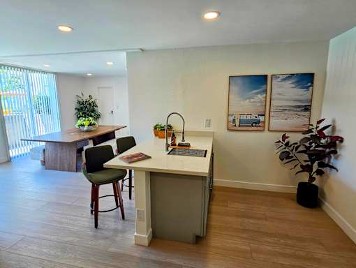 A kitchen with a table and chairs and a plant.