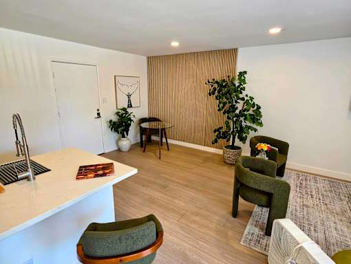 A room with a white counter and green chairs.