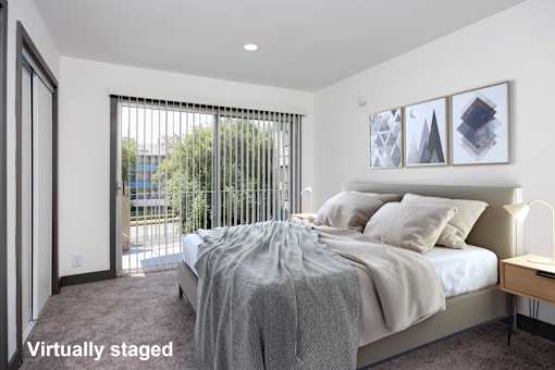 A bedroom with a bed, nightstand, and pictures on the wall.