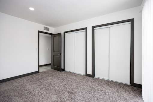 a living room with white walls and doors and a carpet