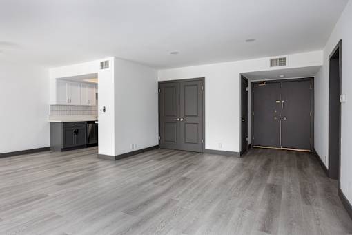 the living room and kitchen of an empty apartment with black doors and white walls