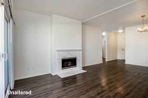 A large, empty room with a fireplace and wooden floors.