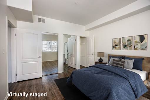 A bedroom with a bed, dresser, and mirrors.