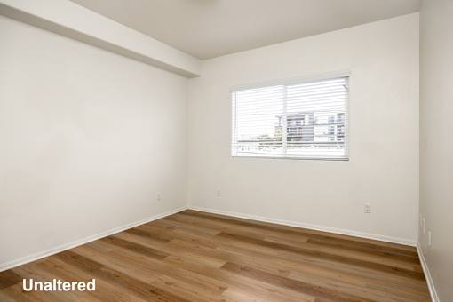 A room with unaltered wooden flooring and a window.