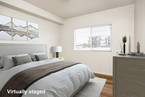 A bedroom with a large bed and a window with blinds.