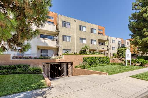 an apartment building with a gated entrance and a sidewalk