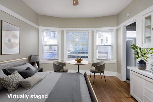 A living room with a grey couch and a table with chairs.