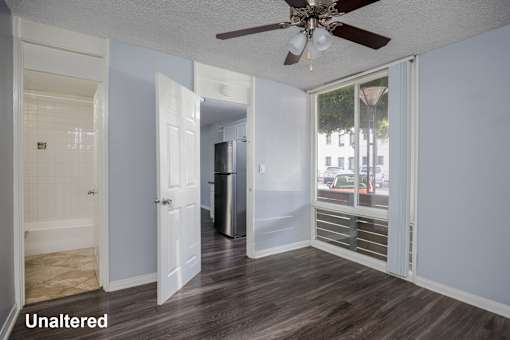 A room with a ceiling fan and a door leading to another room.