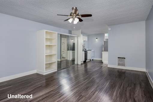 A room with a ceiling fan and unaltered wood flooring.