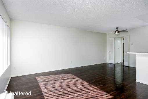 A room with a ceiling fan and a striped rug on the floor.