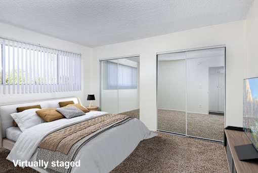 A bedroom with a bed, a mirror, and a lamp.