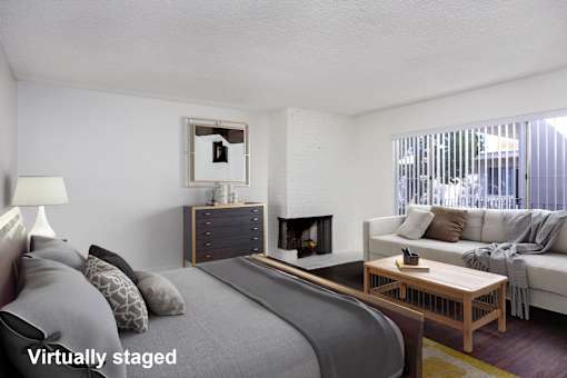 A bedroom with a bed, a couch, a coffee table, and a fireplace.