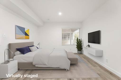 A bedroom with a bed, a couch, a television, and a painting on the wall.