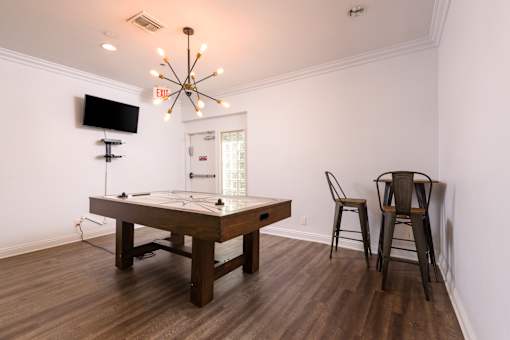 A room with a pool table and chairs.