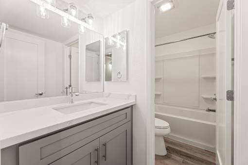 A white bathroom with a sink, mirror, and toilet.