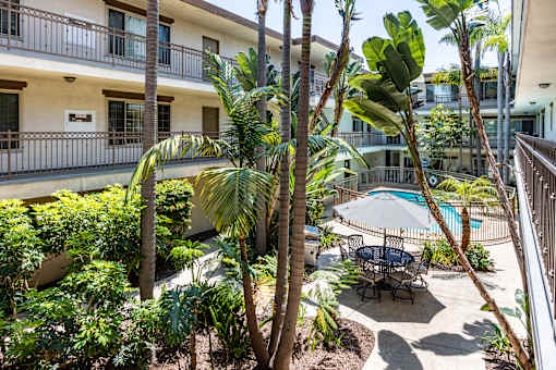 a patio with palm trees and a table and chairs