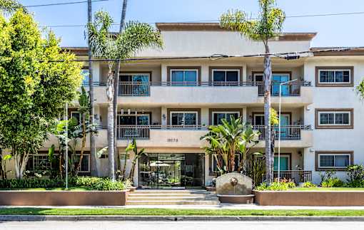 an apartment building with palm trees in front of it