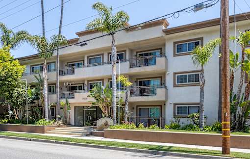 a white apartment building with palm trees in front of it