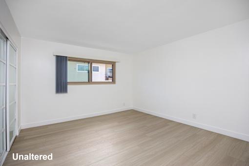 A room with unaltered flooring and a window with a view of buildings outside.