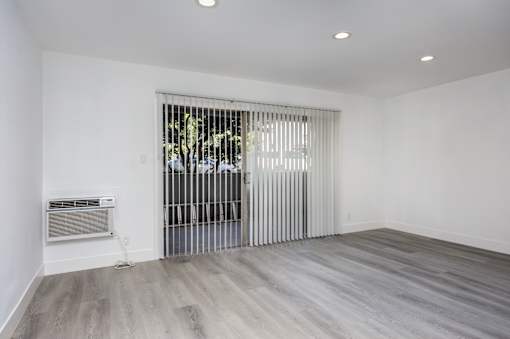 a living room with white walls and a sliding door to a patio