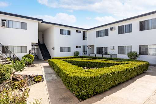 an exterior view of a building with hedges and a courtyard