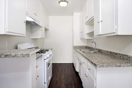 a kitchen with white appliances and granite counter tops and white cabinets