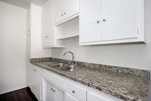 a kitchen with white cabinets and granite counter top and a sink