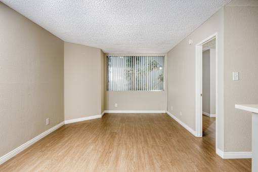 A room with wooden flooring and a window with blinds.