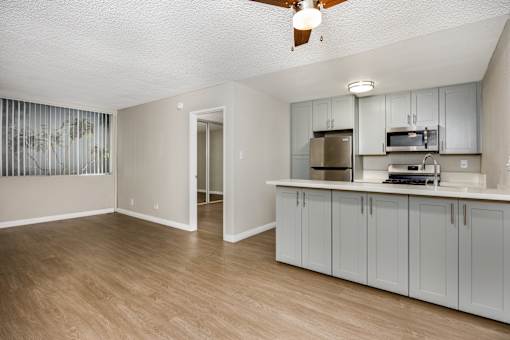 A kitchen with a fan on the ceiling and a countertop with a microwave and toaster.